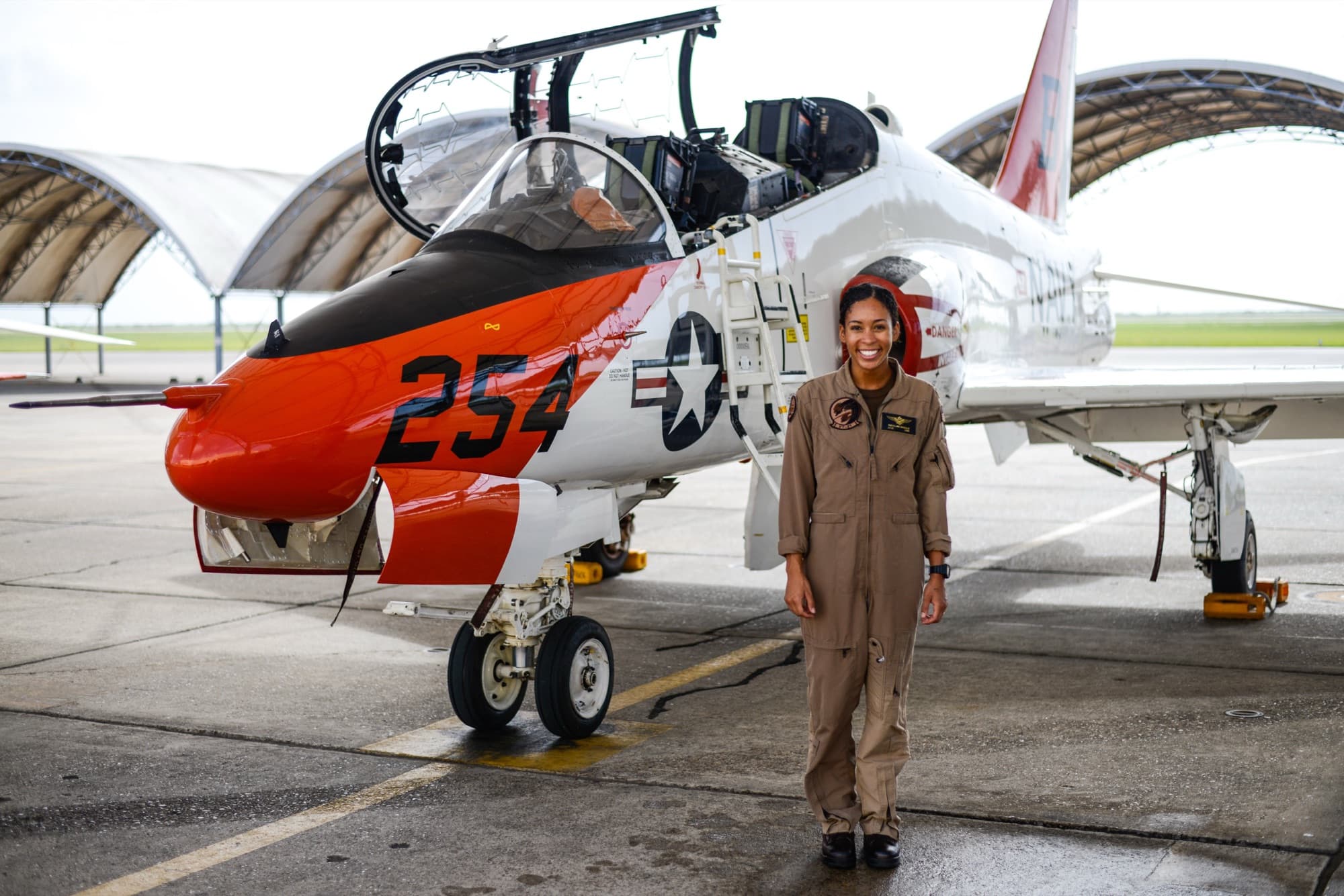 A Black Navy aviator standing in front of a T-45 Goshawk trainer jet