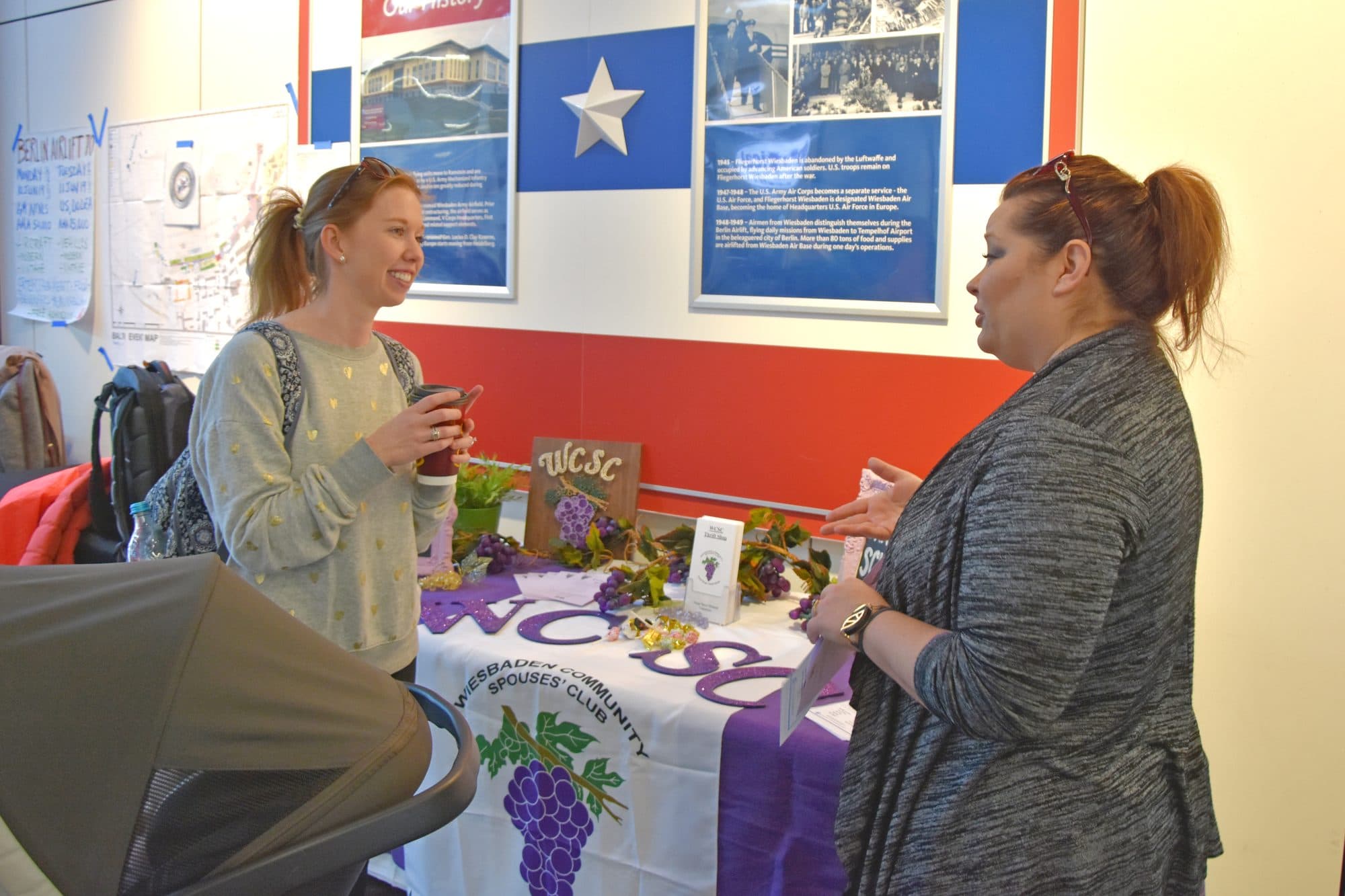 A military spouse talks with a community spouses club volunteer at a volunteer fair in Wiesbaden, Germany