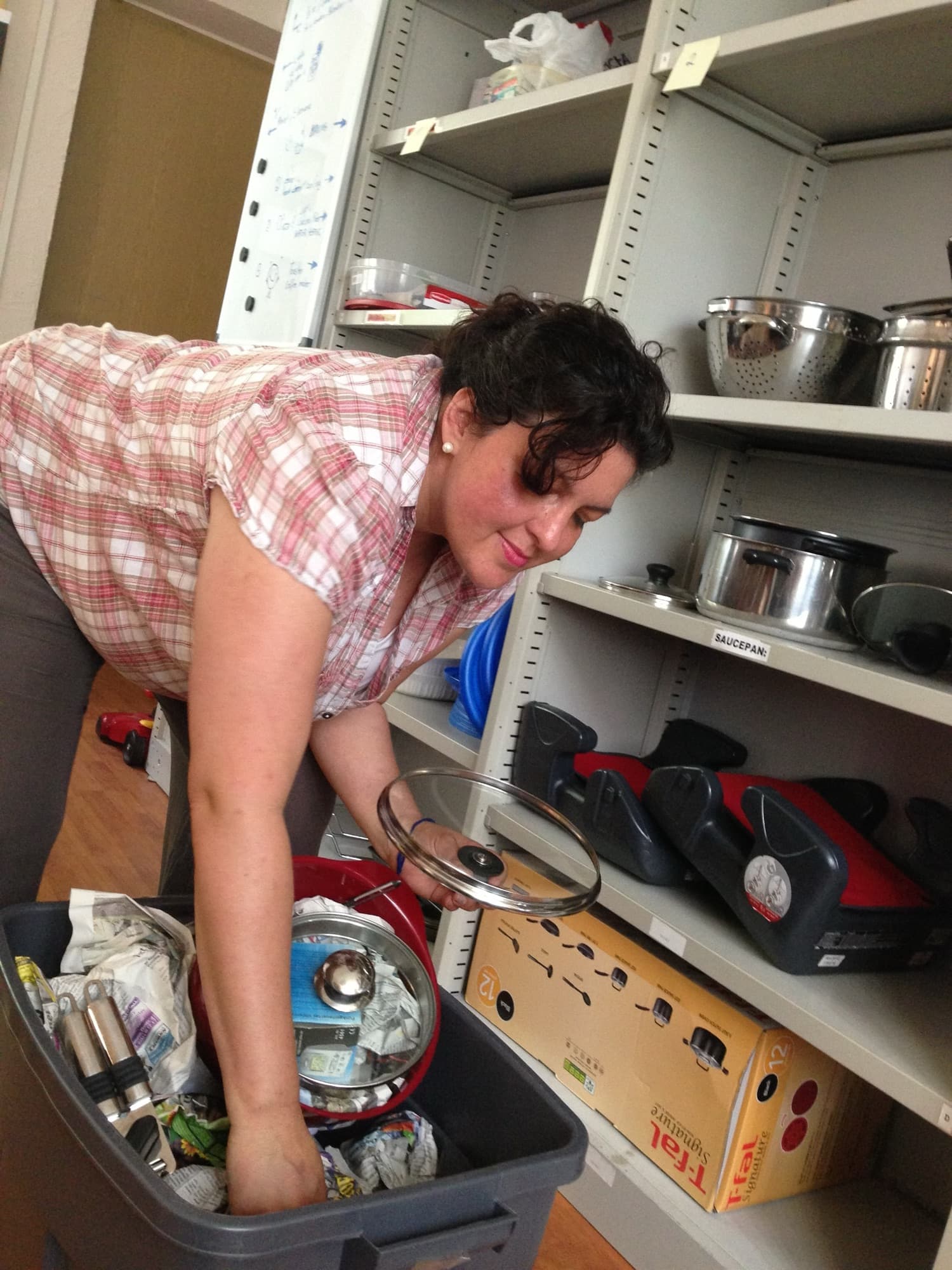 A civilian relocation assistant sorts household goods in an Army Community Service lending closet