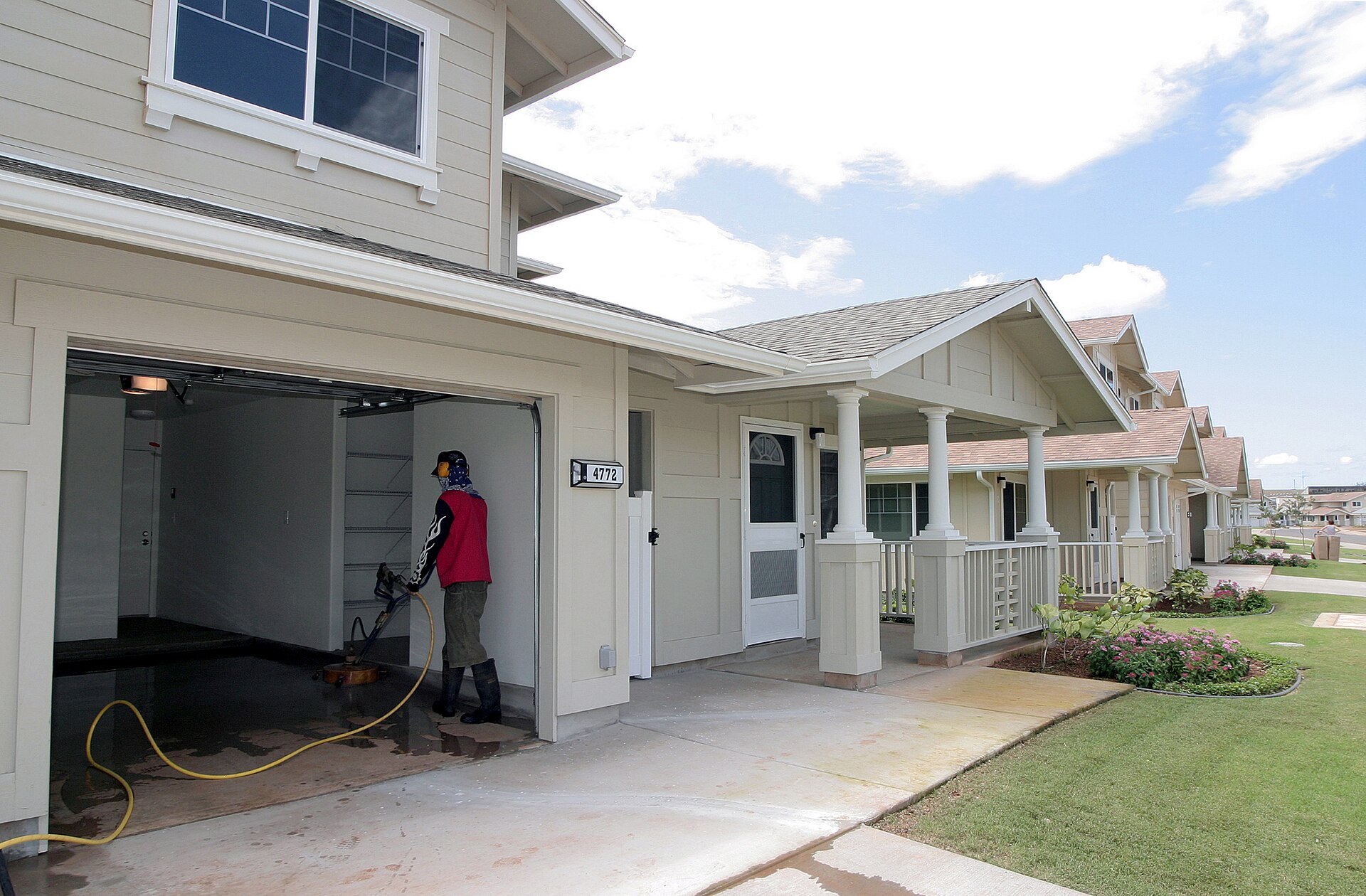 A Navy family waits on the lawn while movers deliver household goods